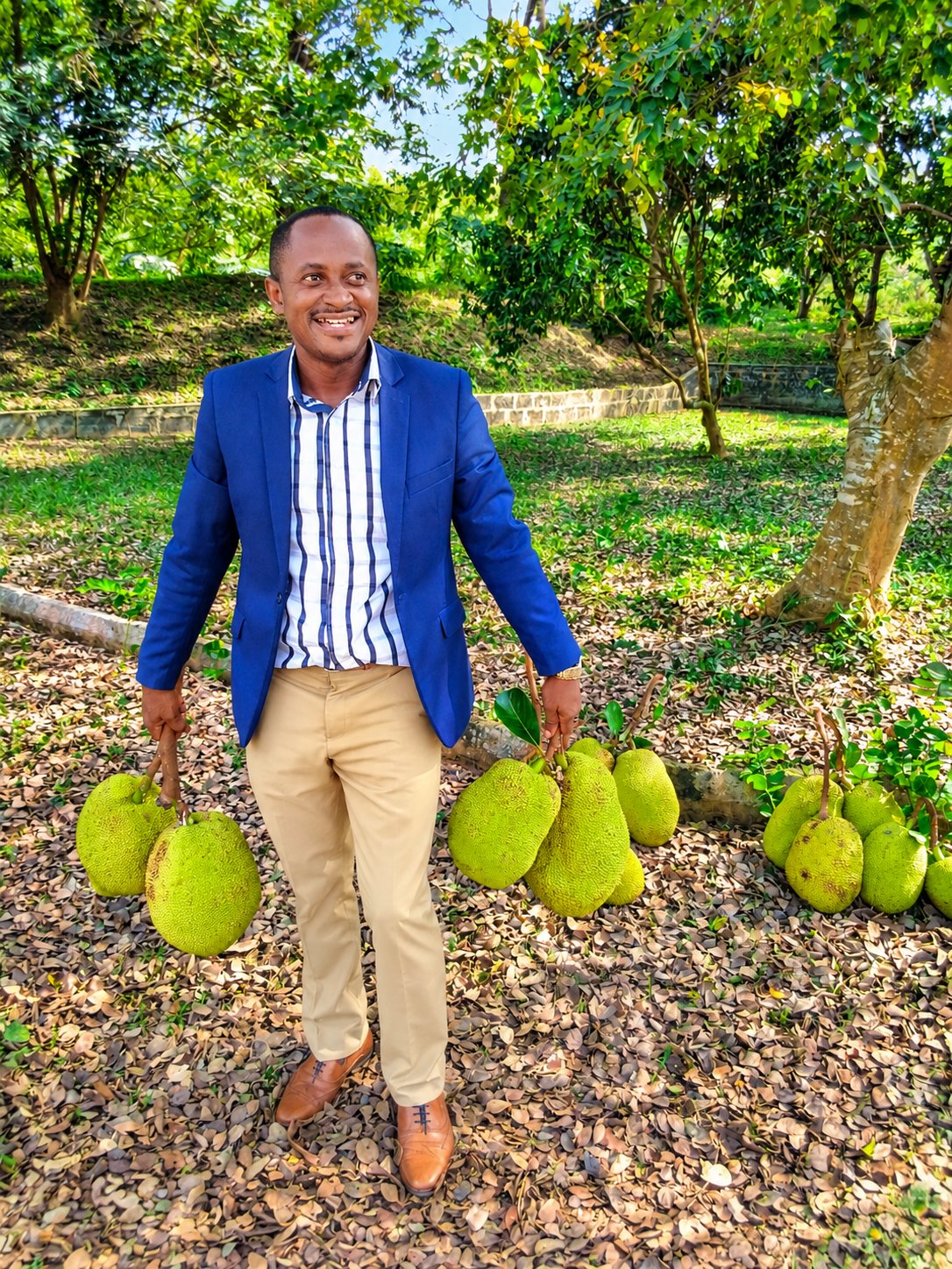 Dr. Kwadwo Kusi Amoah smiling as he holds freshly harvested jackfruit in a fruit orchard